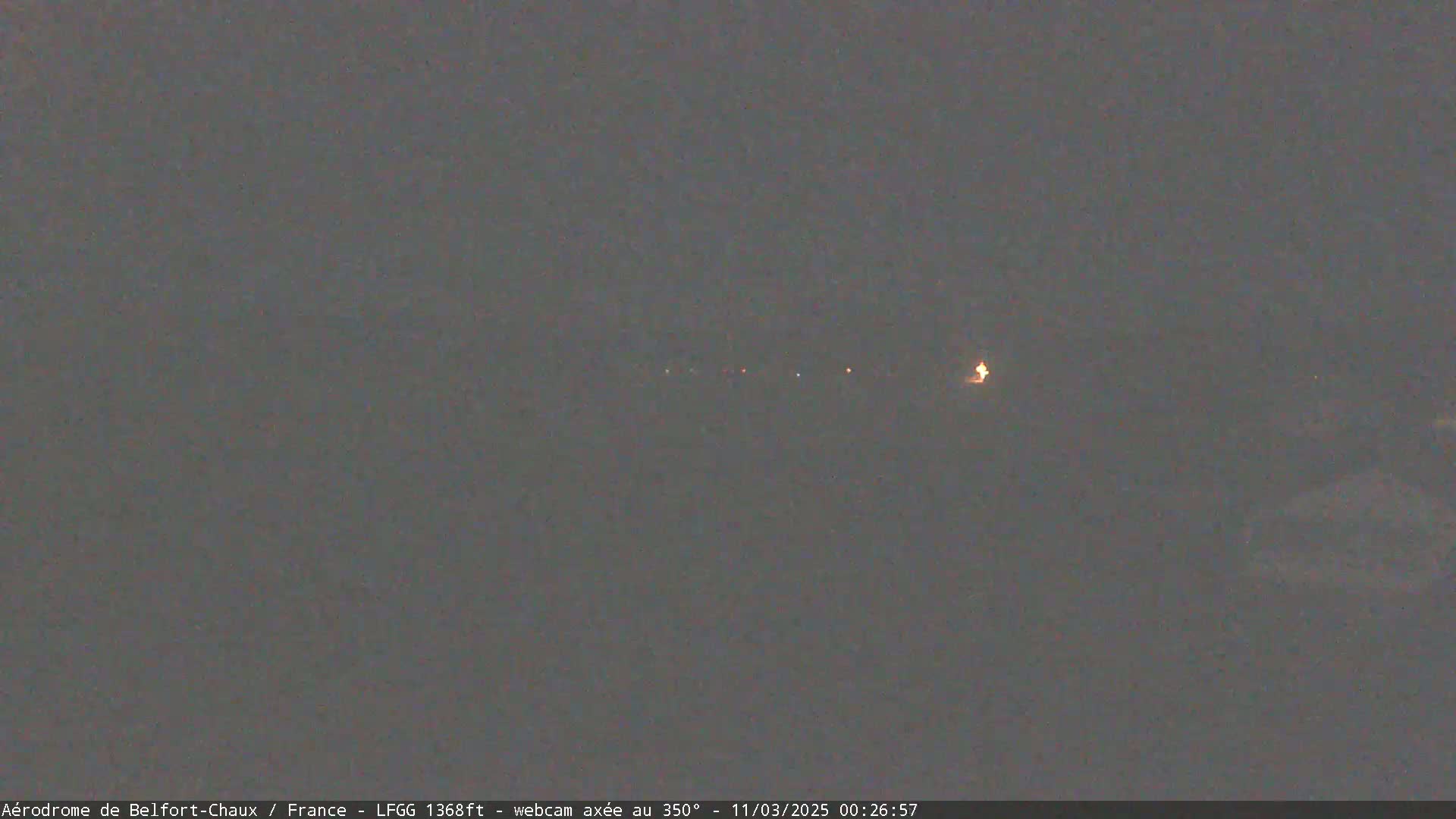 A dark, nighttime scene shows a distant line of faint lights.