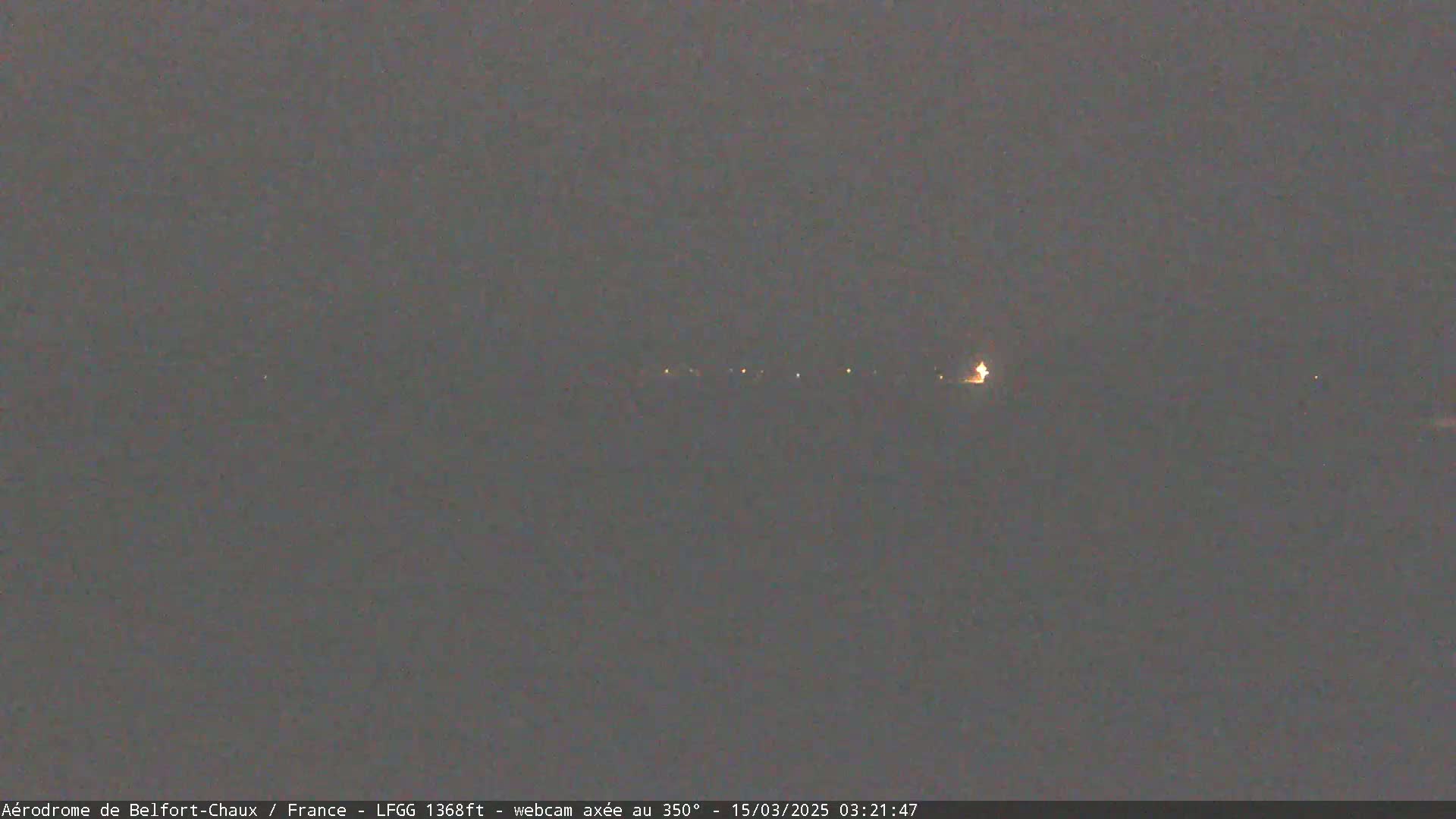 A dimly lit, flat landscape at night is visible under a dark sky.
