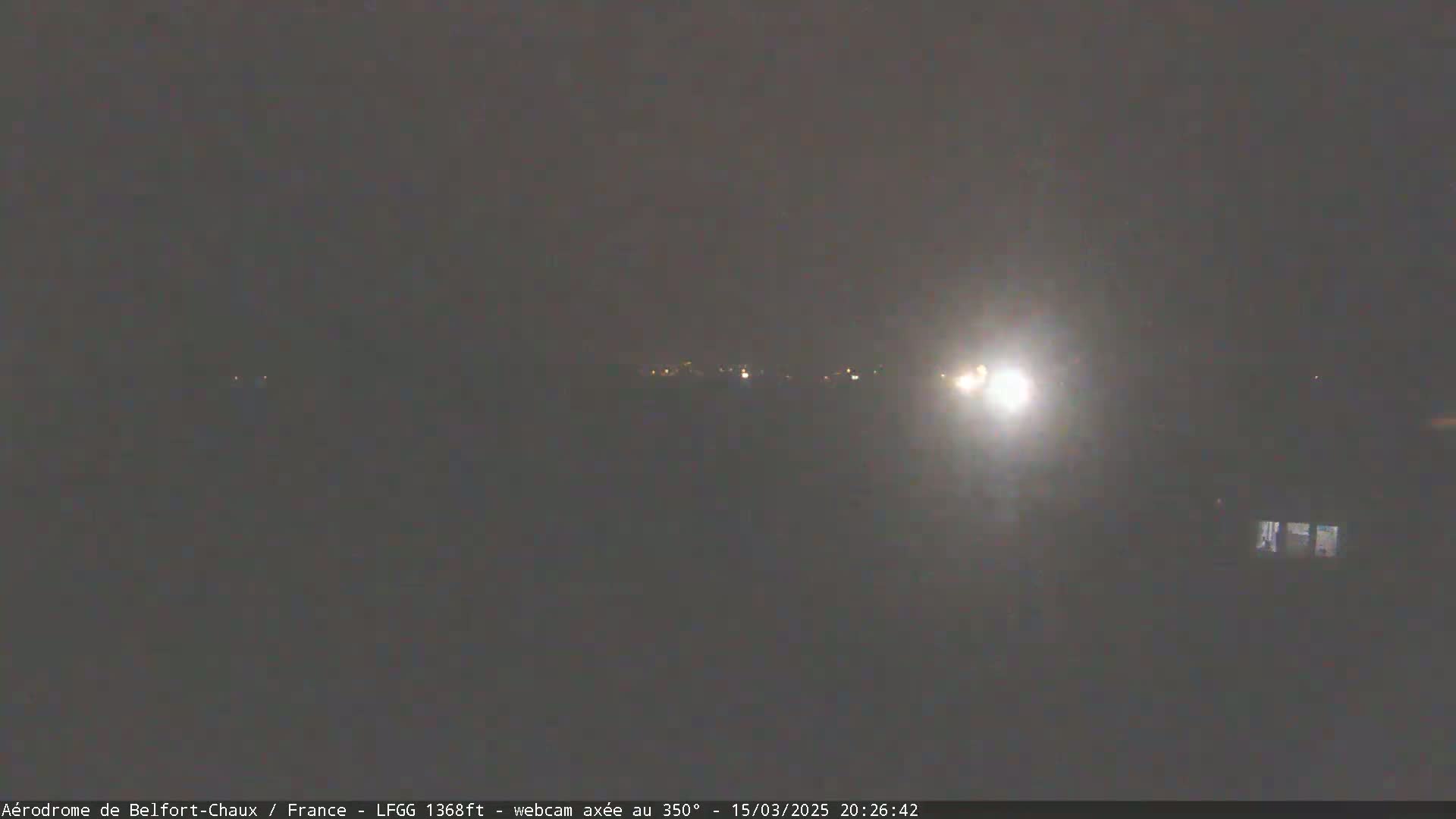 A nighttime view of dimly lit buildings in the distance under a dark, possibly overcast sky.