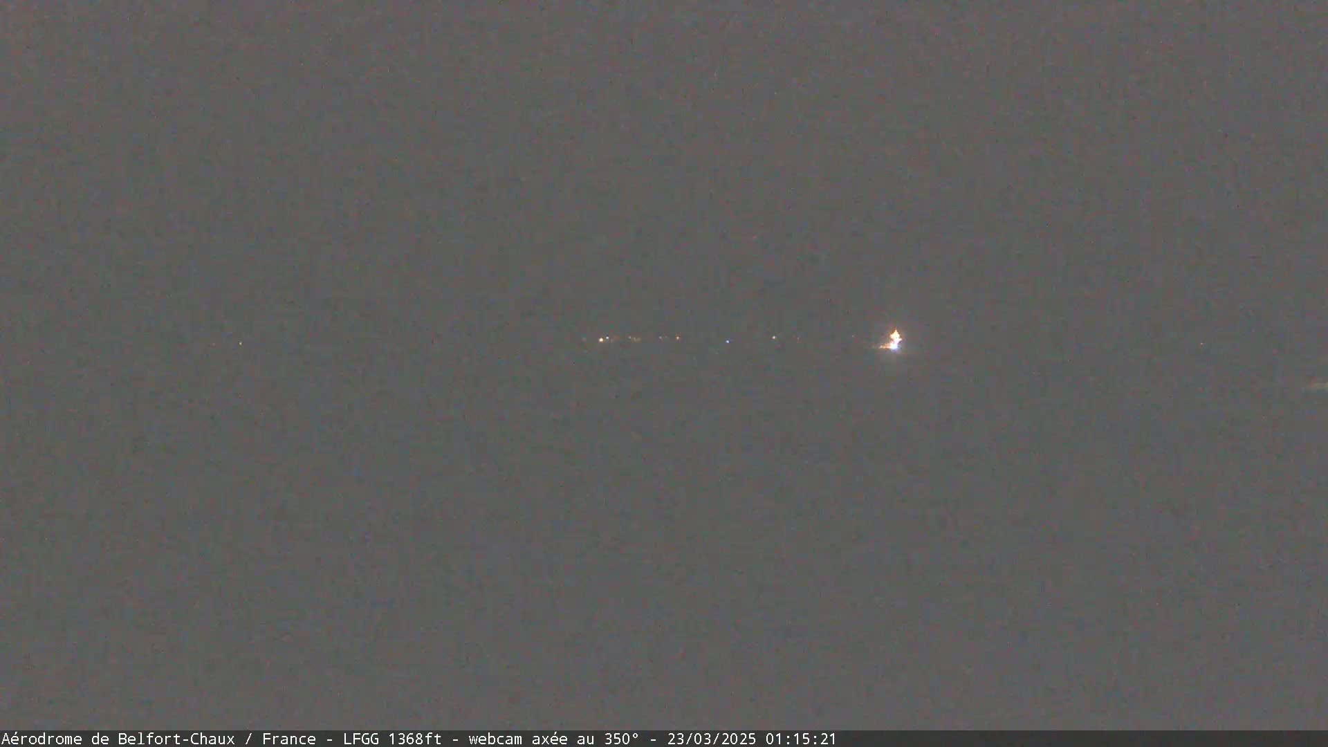 A dark, nighttime scene shows a long, horizontal line of faint lights in the distance.