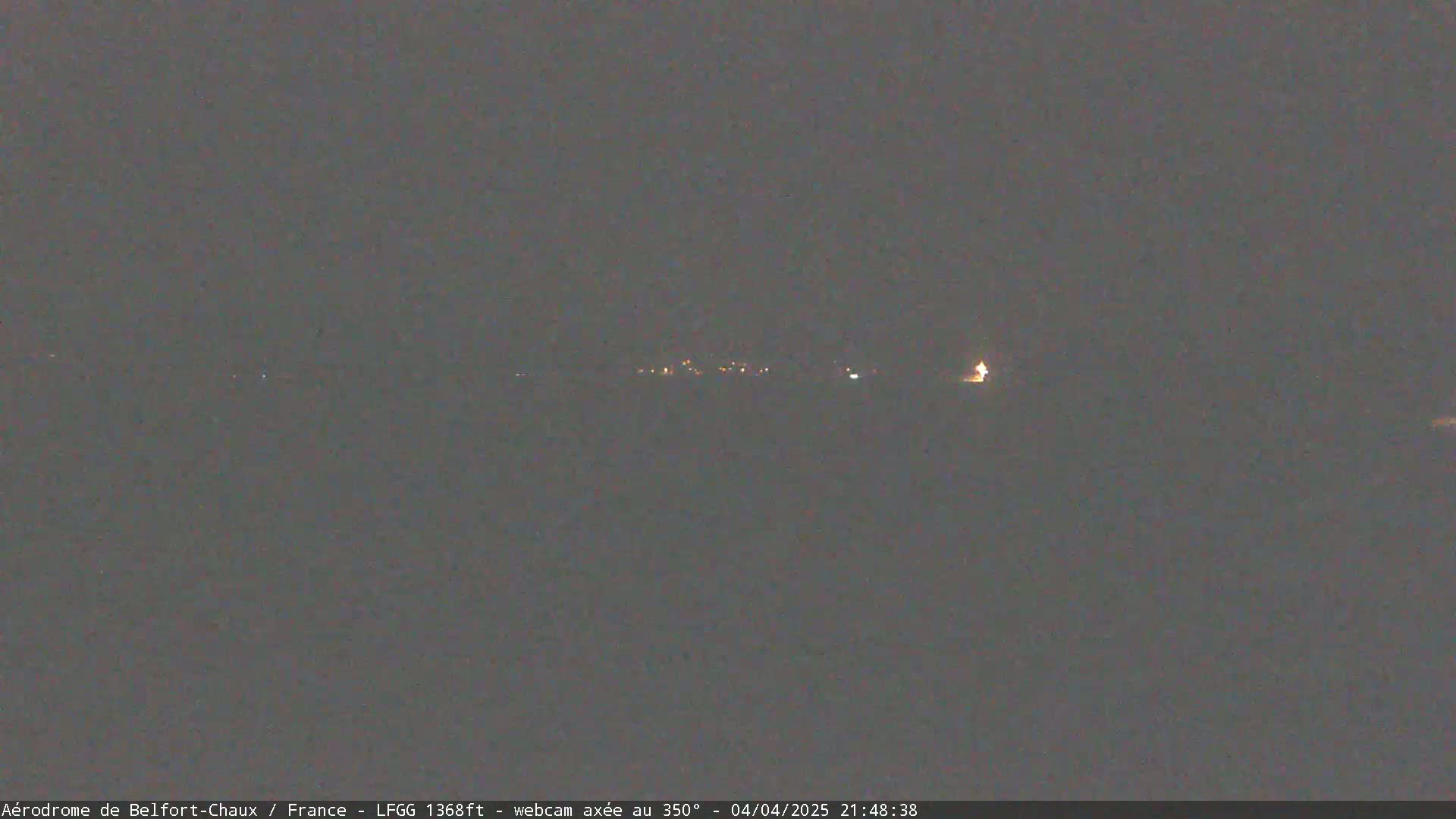 A dark, nighttime view of a distant line of lights, possibly a small town or village, under a dark, clear sky.