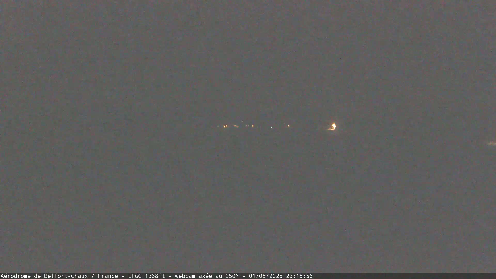A dark, nighttime scene shows a few distant lights on the horizon under a gray sky.