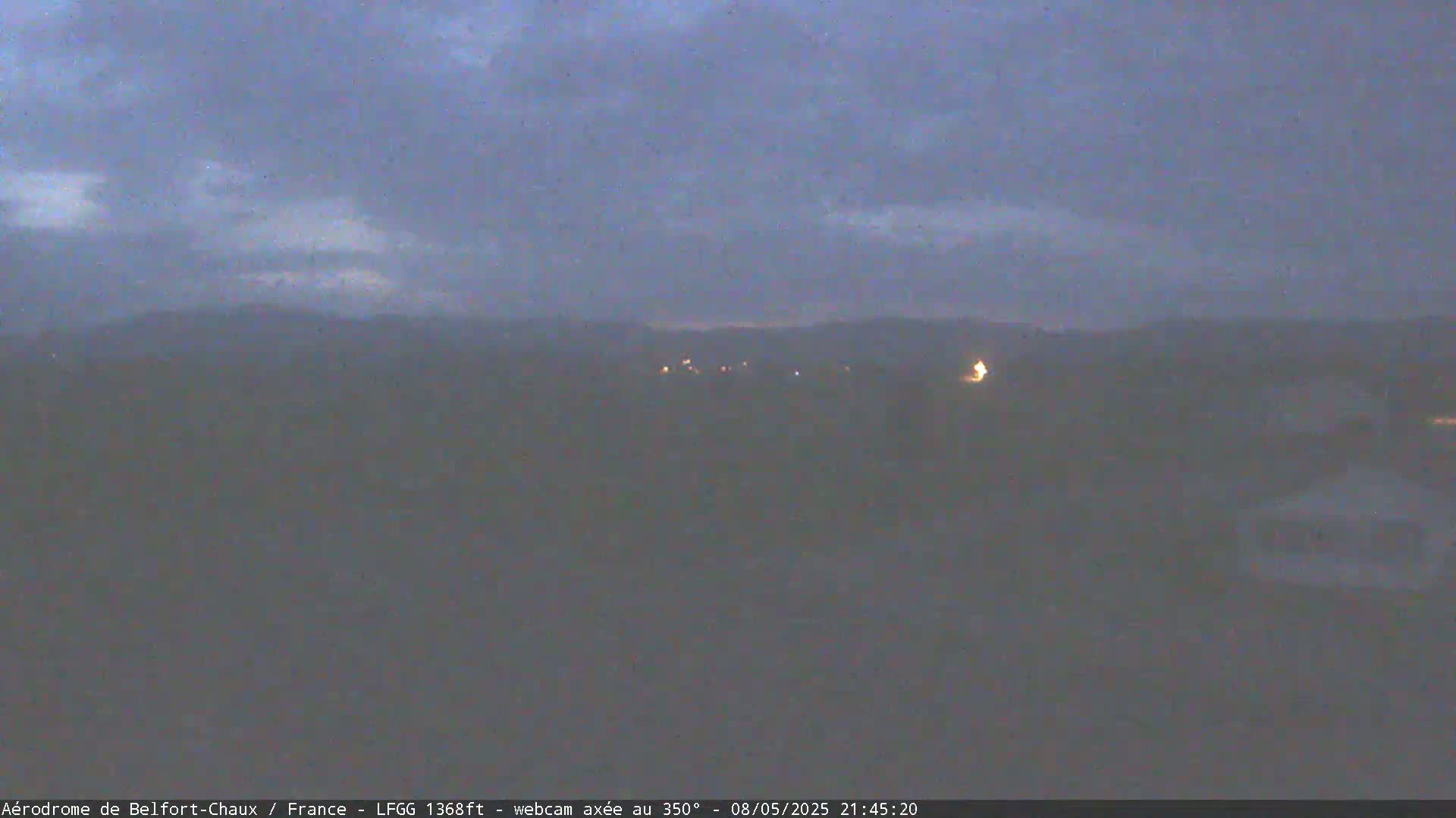 A hazy, dark-blue twilight sky hangs over a dimly lit, distant landscape.