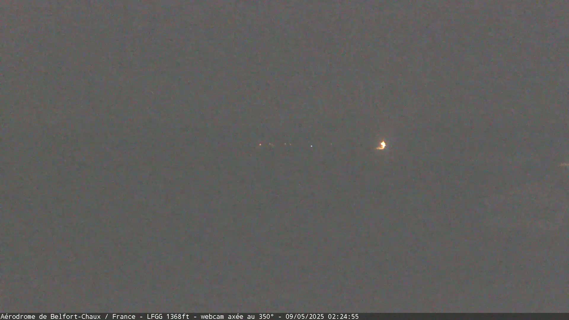 A dark, blurry nighttime scene shows a few distant lights on the horizon.