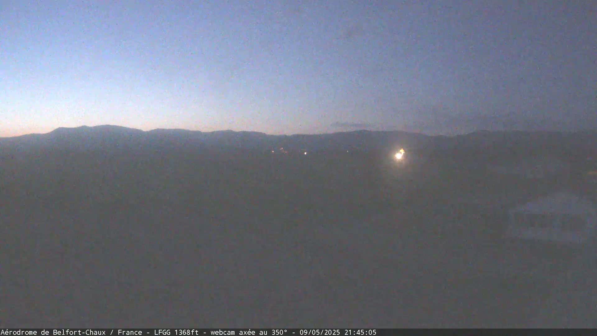 A hazy twilight view shows a dark mountain range in the distance under a dusky sky.