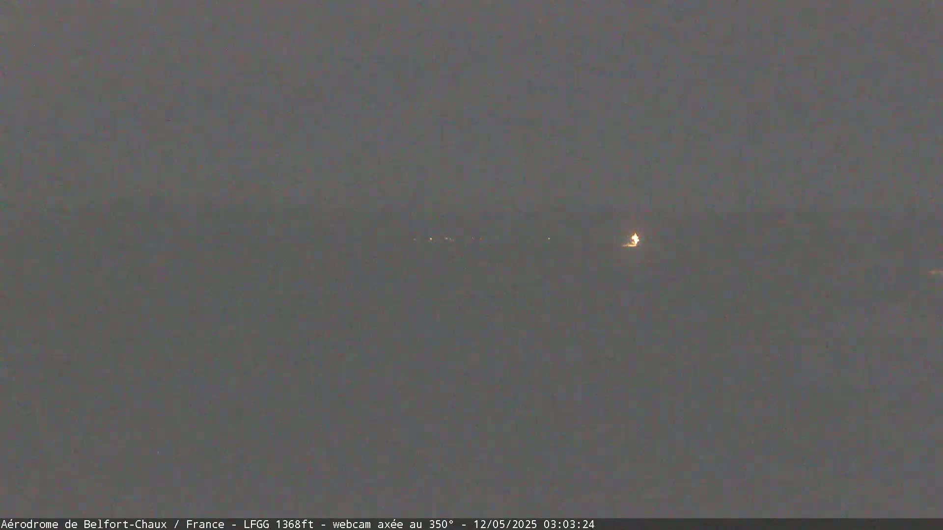 A dark, nighttime scene shows a few distant lights on the horizon under a gray sky.