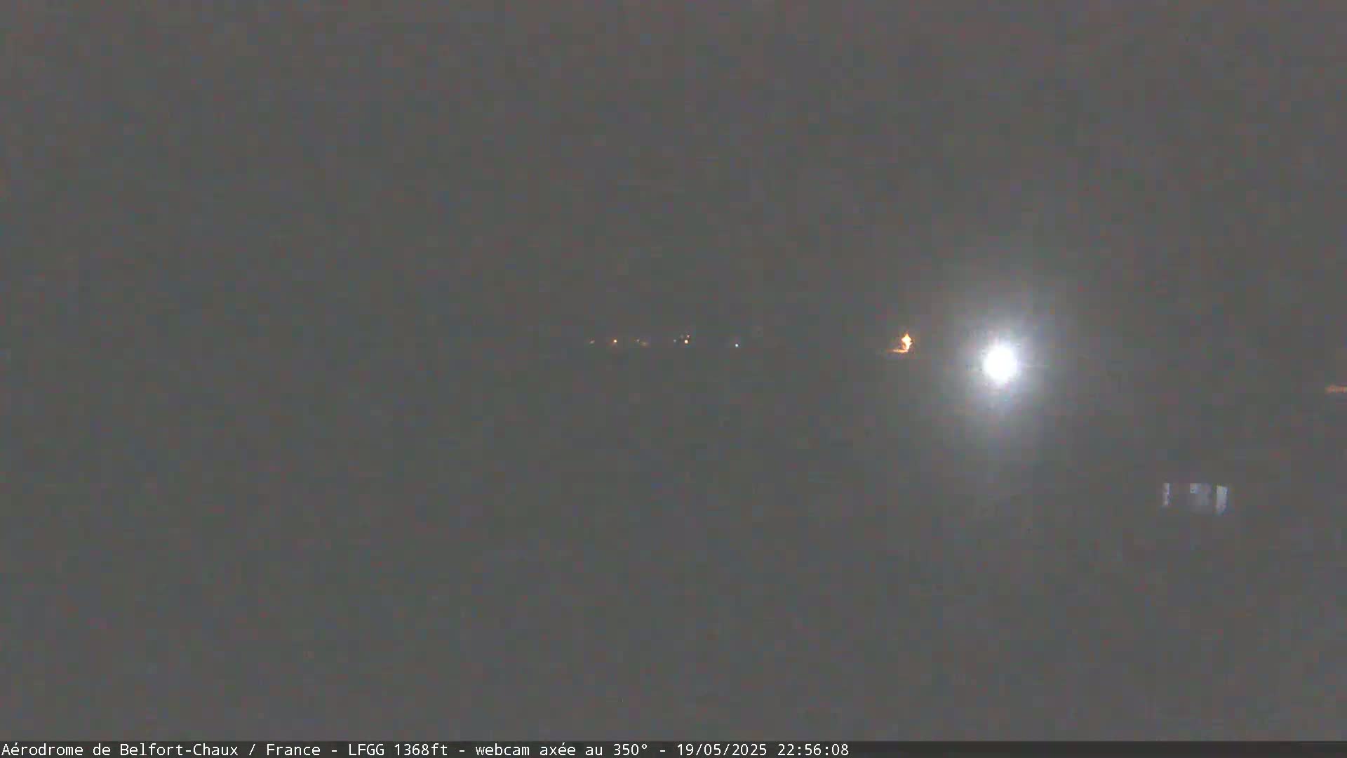 A dark, nighttime scene shows a few distant lights under a bright, hazy moon.