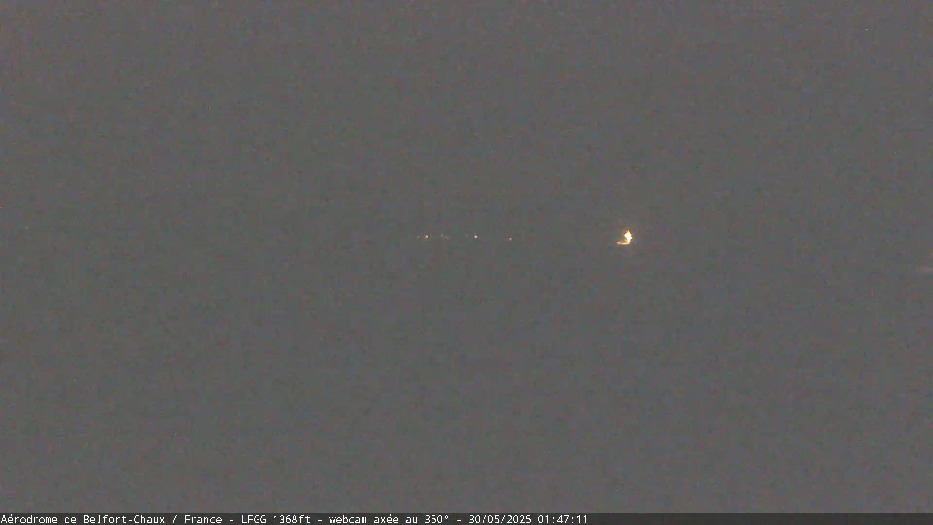 A dark, nighttime scene shows a faint line of lights in the distance.