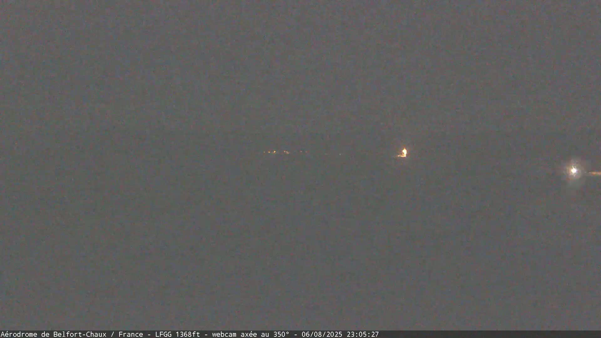 A nighttime long shot shows a few distant lights on the horizon under a dark, overcast sky.