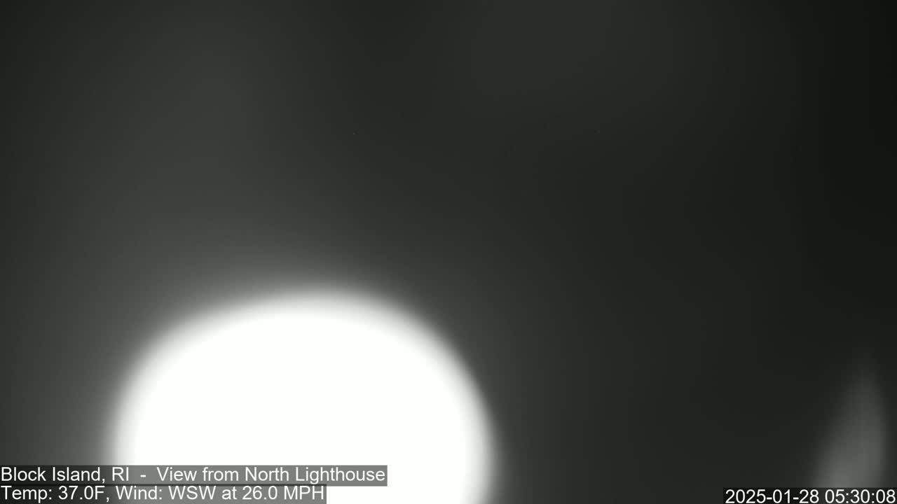 A bright white light dominates the lower center of a dark, blurry outdoor image under a dark, windy sky.