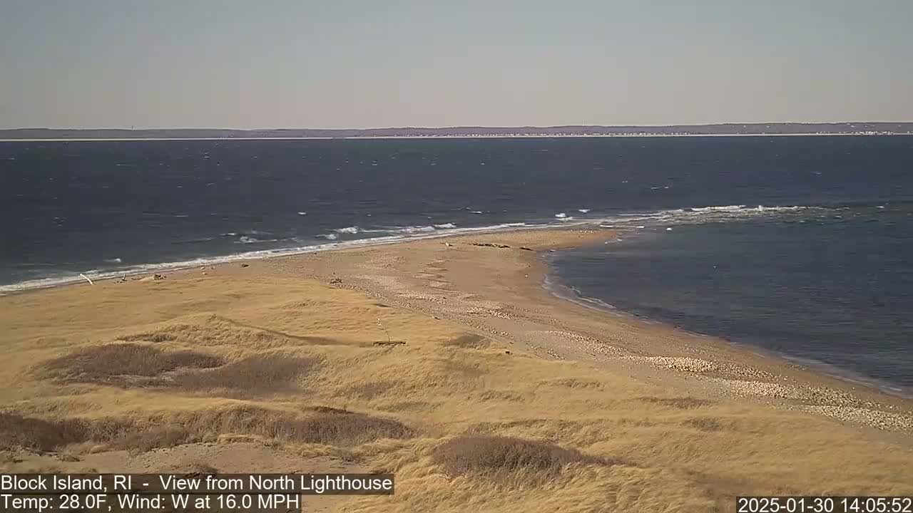 A sandy beach and dunes extend into a choppy ocean under a clear sky with a 16 mph westerly wind.