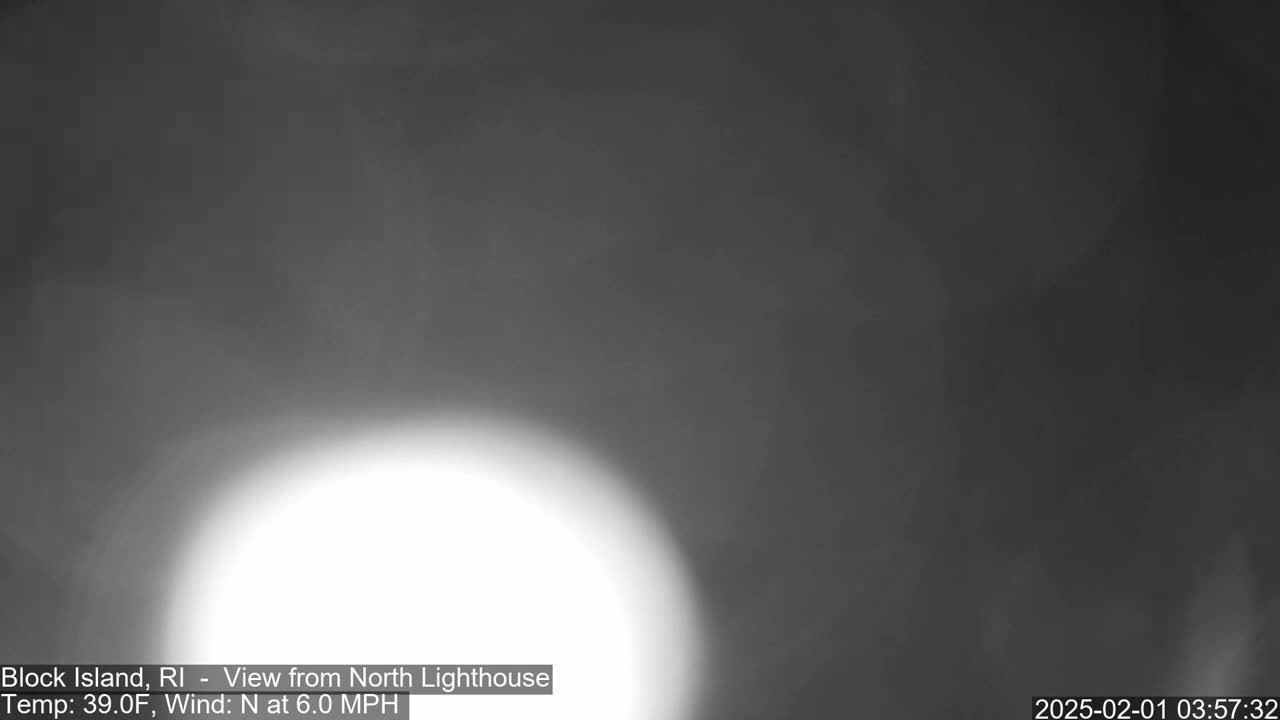 A bright, hazy white light dominates the center of a blurry, dark gray and overcast image.