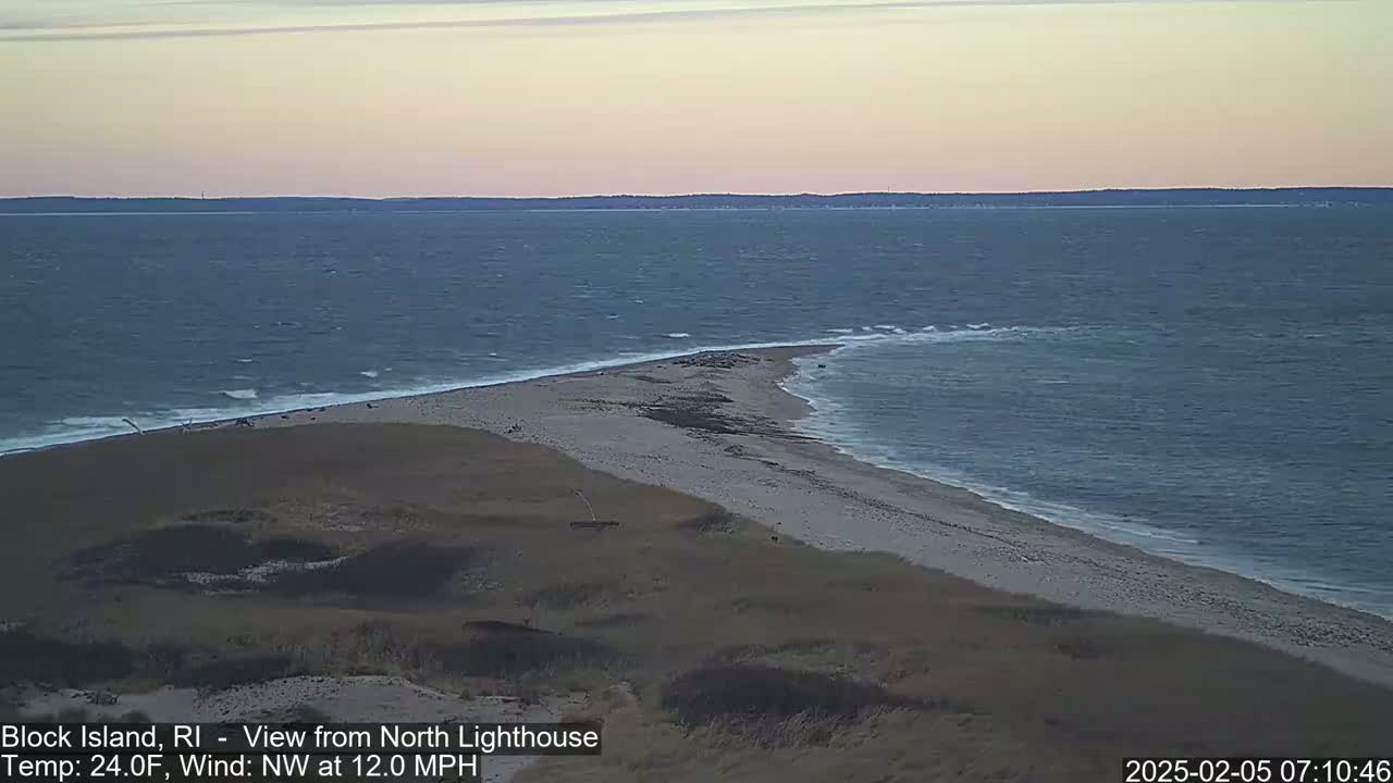 A sandy, coastal point juts into a choppy sea under a pale, twilight sky.