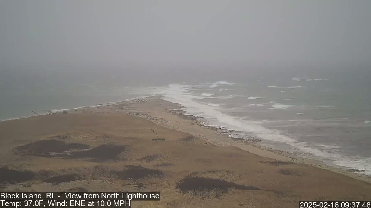 A hazy, windy day shows a sandy shoreline with waves crashing on the beach.