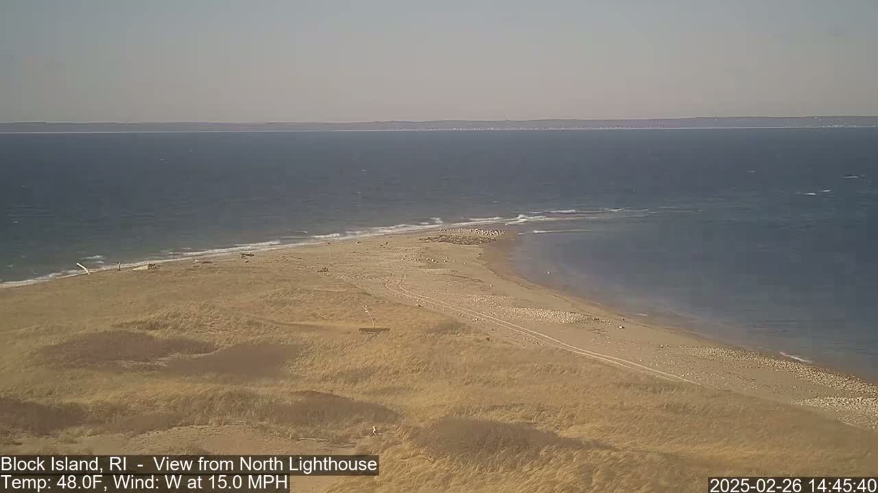 A sandy beach and dunes extend into a choppy ocean under a clear sky with a 15 mph westerly wind.