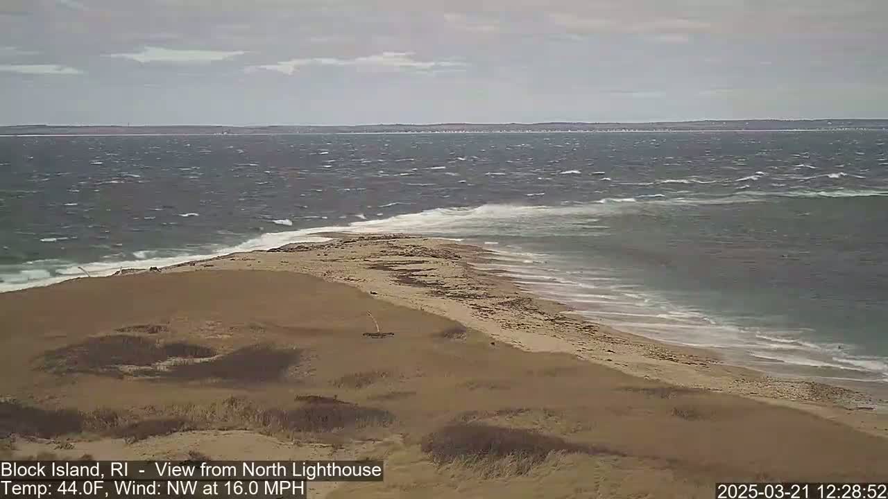 A sandy beach and dune landscape meet a choppy ocean with a northwest wind blowing at 16 mph.