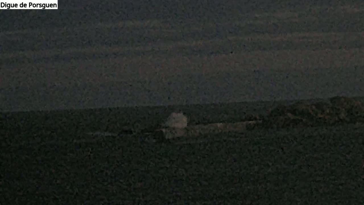 A dark, possibly overcast sky overlooks a dark body of water with a small, light-colored splash near a dark shoreline.
