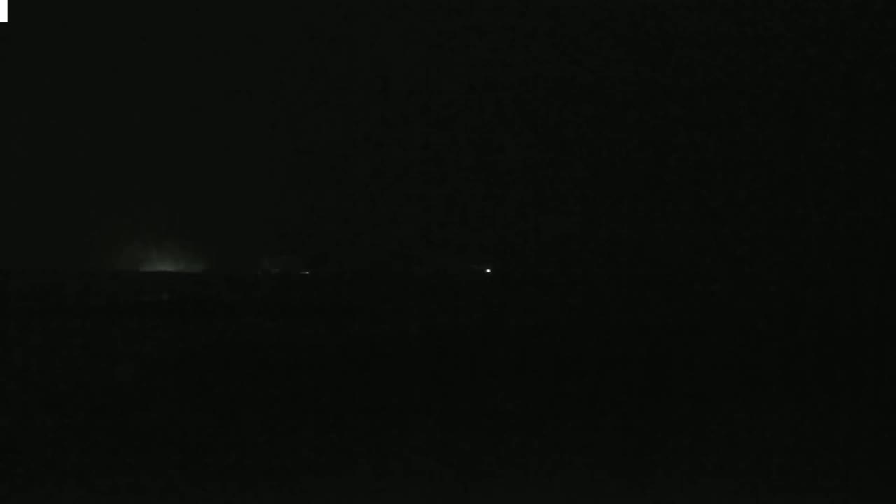 A dark, nighttime scene shows a faint, bright horizon line with a few distant lights.