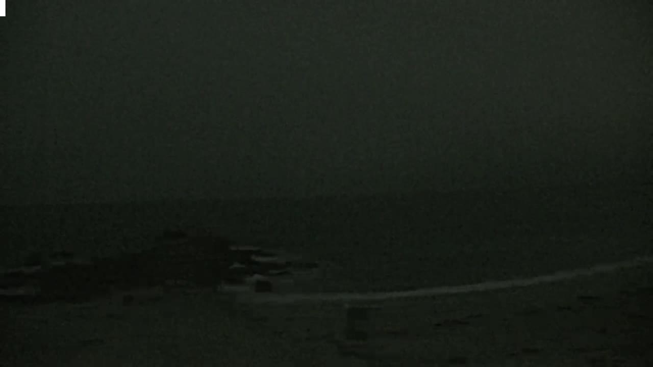 A dark, overcast sky hangs over a mostly obscured shoreline with dark water visible in the distance.