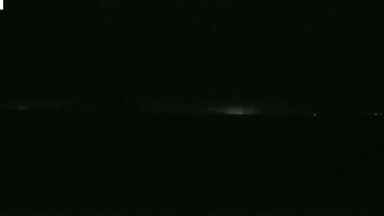 A low horizon line shows faint, distant lightning illuminating a dark, nighttime landscape.