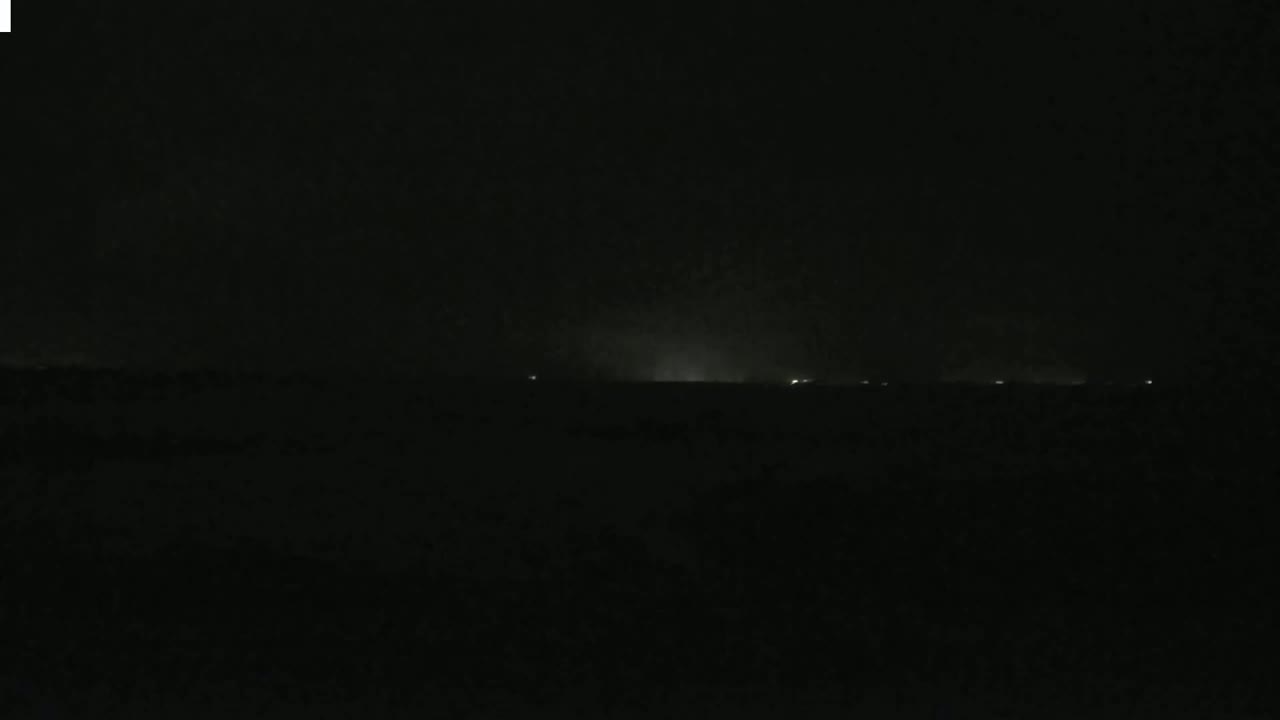 A dark, nighttime landscape with a faint, luminous horizon line possibly indicating distant lights.