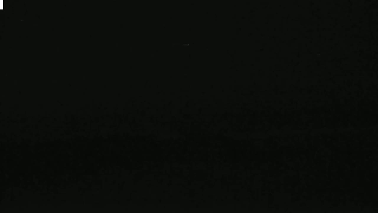 A dark, nighttime scene shows a very faint light in the distance.