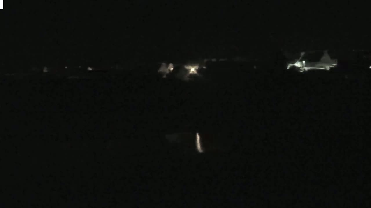 Faint lights from a distant town are visible at night.
