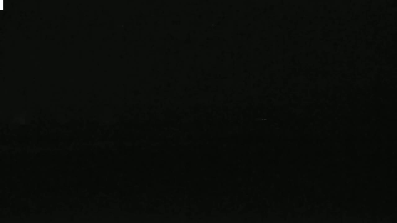 A very dark image shows a mostly black scene with subtle variations in shading.