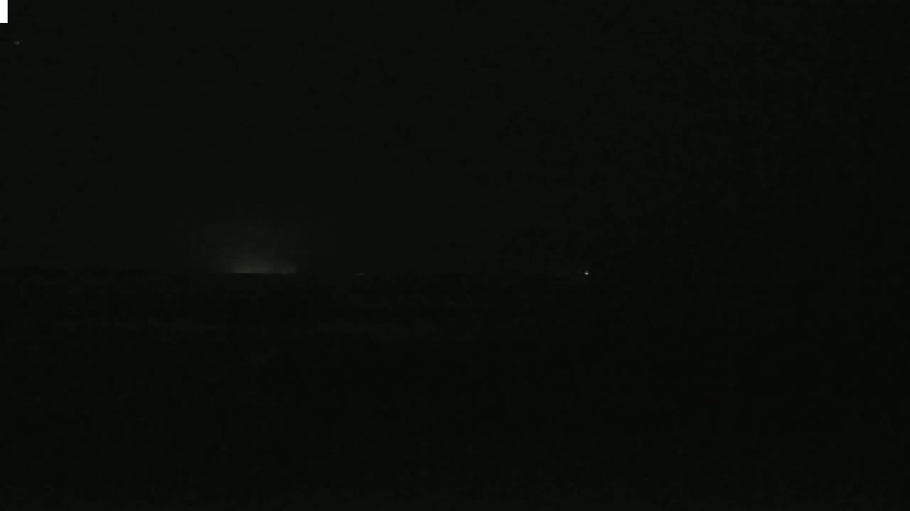 A dark, nighttime landscape is visible with a faint glow on the horizon.