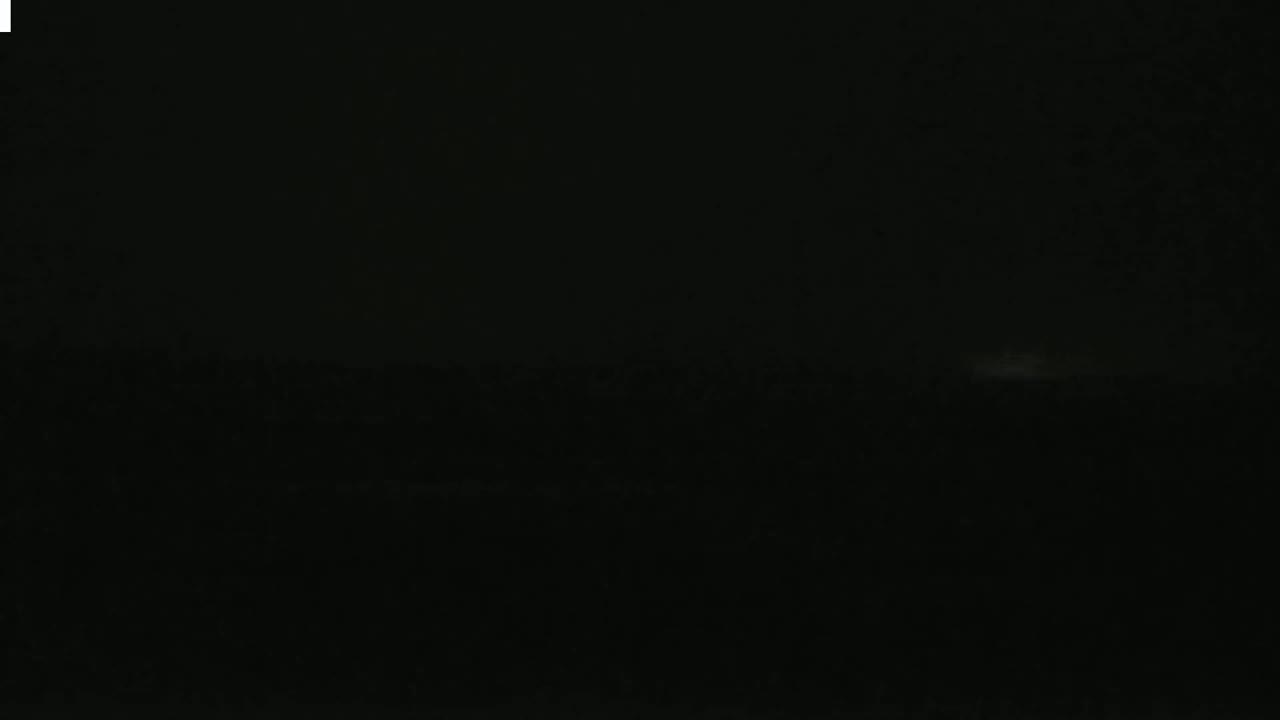 A very dark, nighttime scene shows a faint, horizontal band of lighter gray near the bottom, possibly a distant horizon.