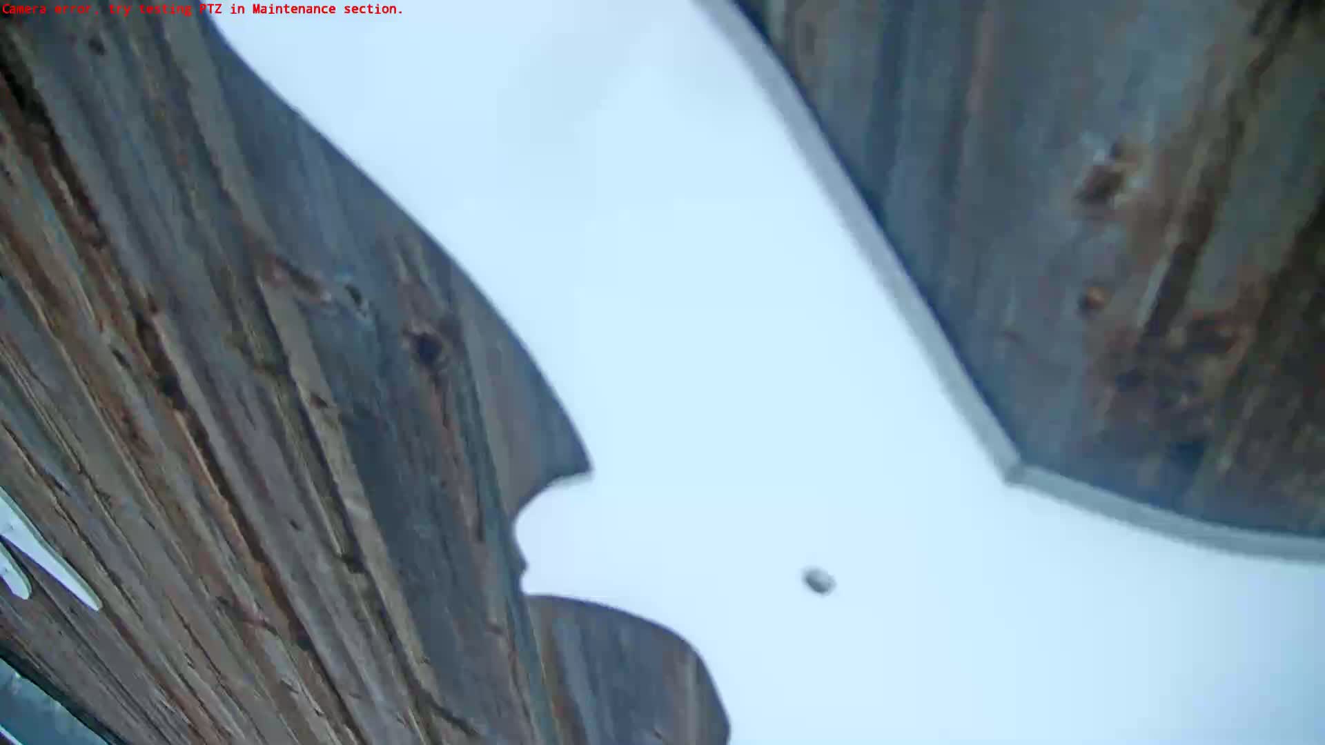 A low-angle view shows a white surface curving over dark brown, vertically-oriented wooden planks.