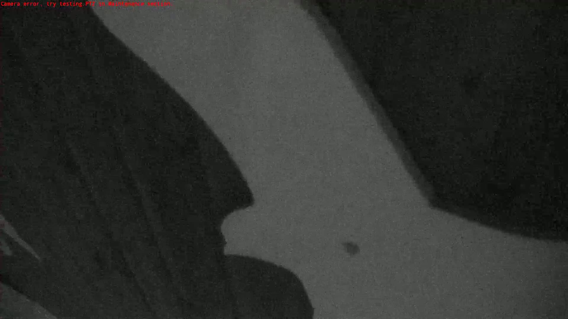 A grainy, low-light image shows dark shadows cast on a light gray surface.