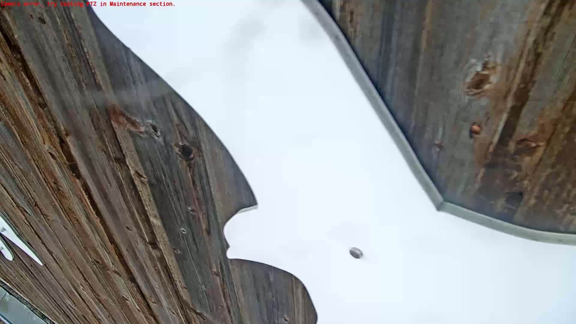 A large white object, possibly a piece of equipment or a design element, is partially visible against a backdrop of dark brown wooden planks.