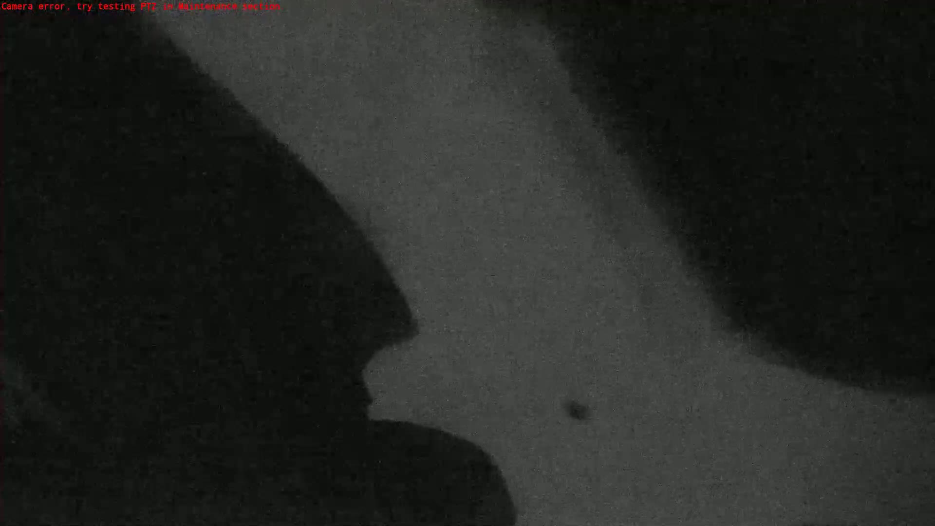 A grainy, dark image shows a shadowy figure to the left and a mostly dark area to the right.
