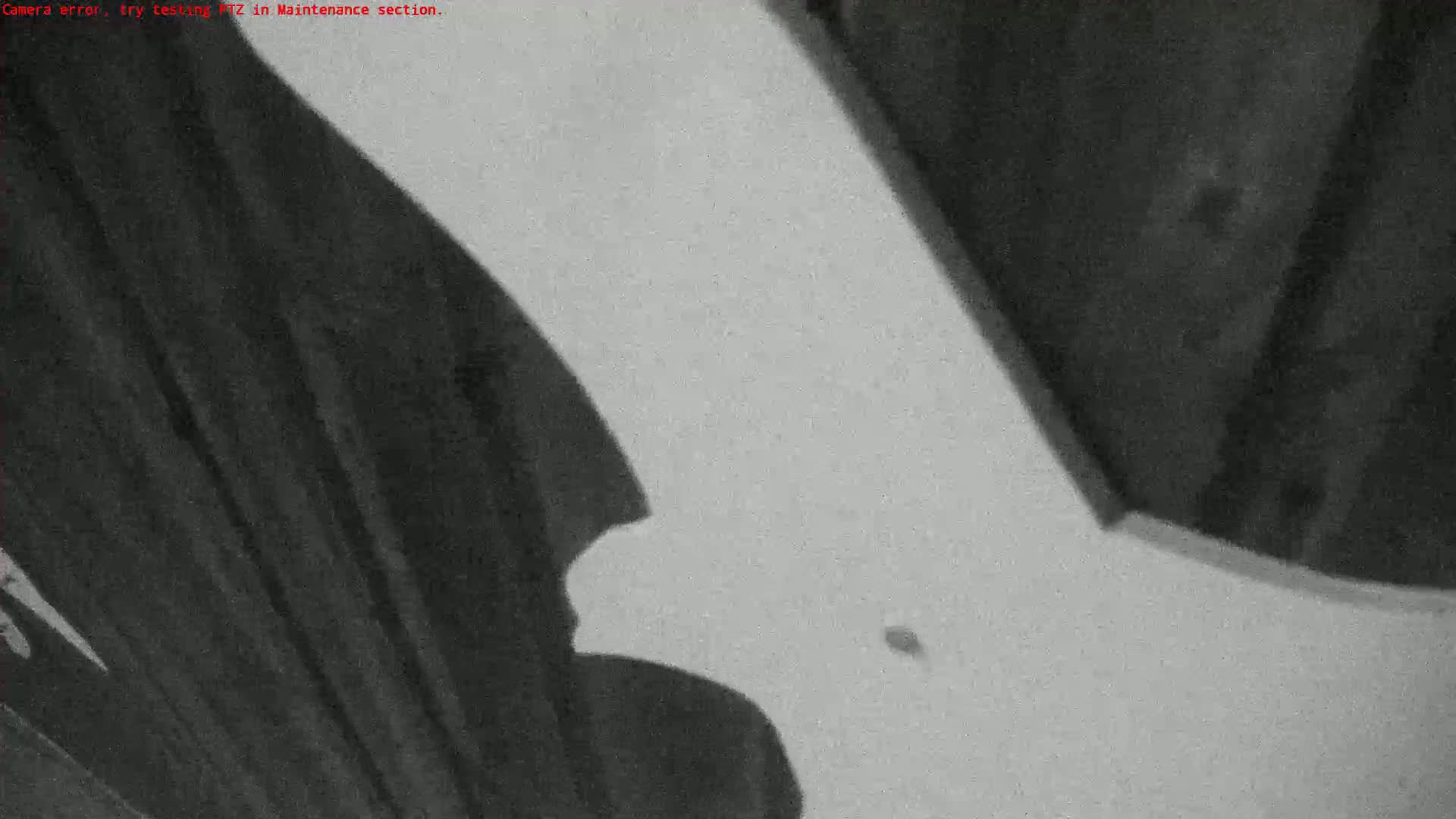 A low-angle, grainy close-up shows a large, light-colored, possibly curved surface with dark shadows cast upon it.