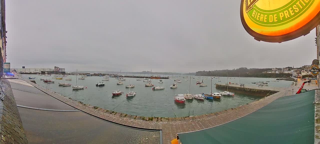A harbor filled with numerous small boats is viewed from a waterfront patio on an overcast day.