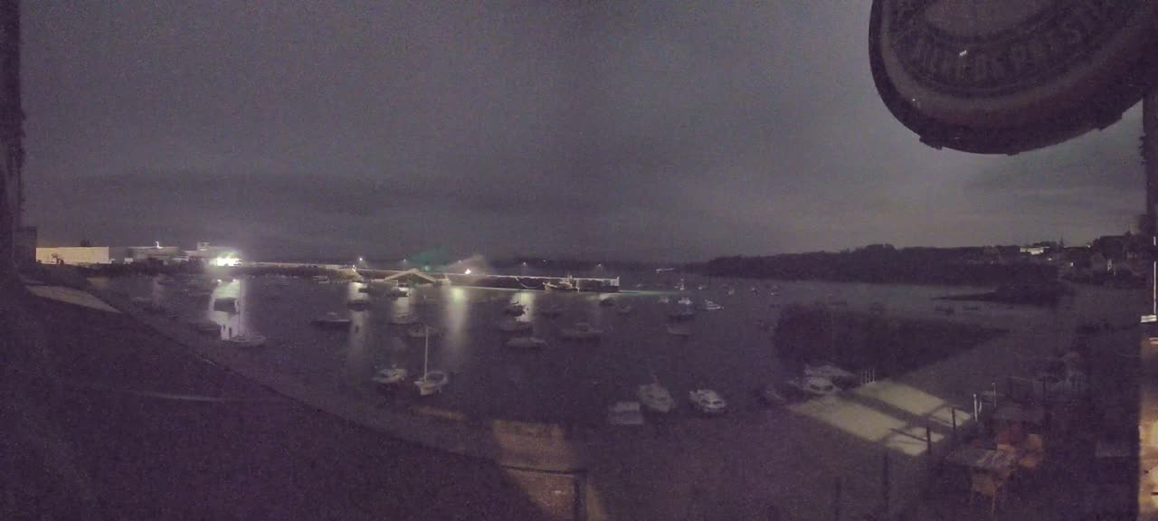 A nighttime view of a harbor filled with boats under a dark, overcast sky.