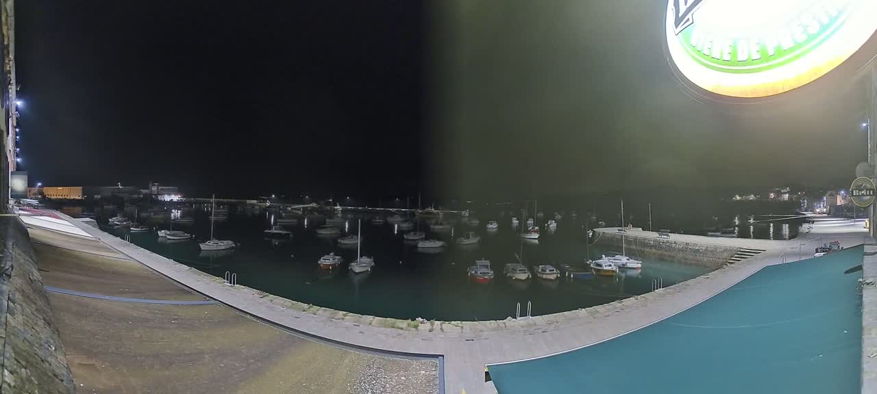 A nighttime view of a harbor filled with numerous small boats, under a dark sky.
