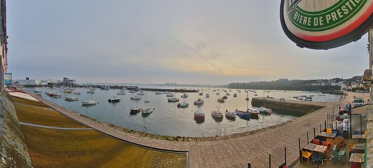 A harbor filled with numerous small boats under a cloudy, overcast sky.