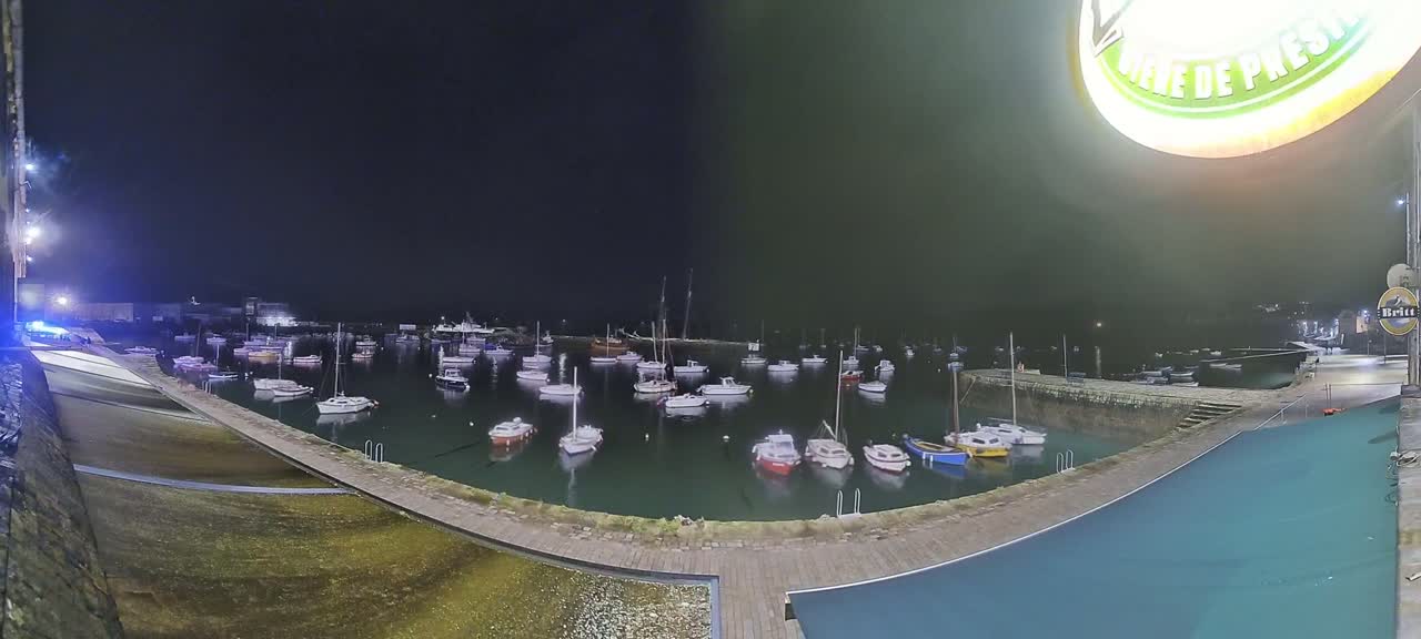 A nighttime view of a harbor filled with numerous small boats, under a dark, overcast sky.