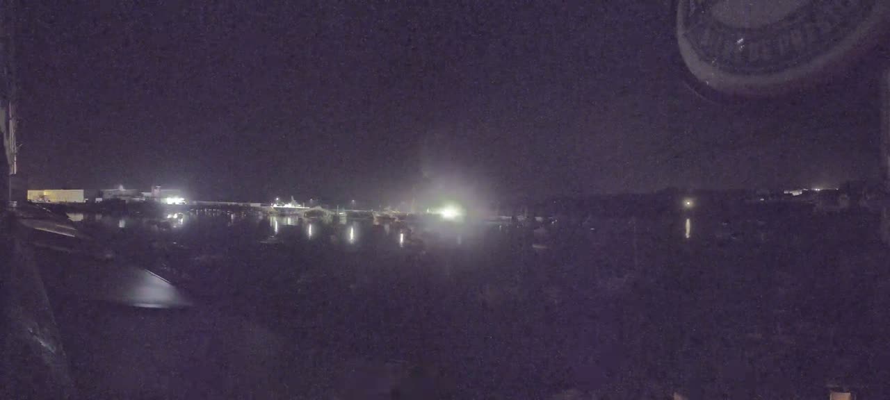 A nighttime view of a calm body of water with lights from buildings and boats in the distance.
