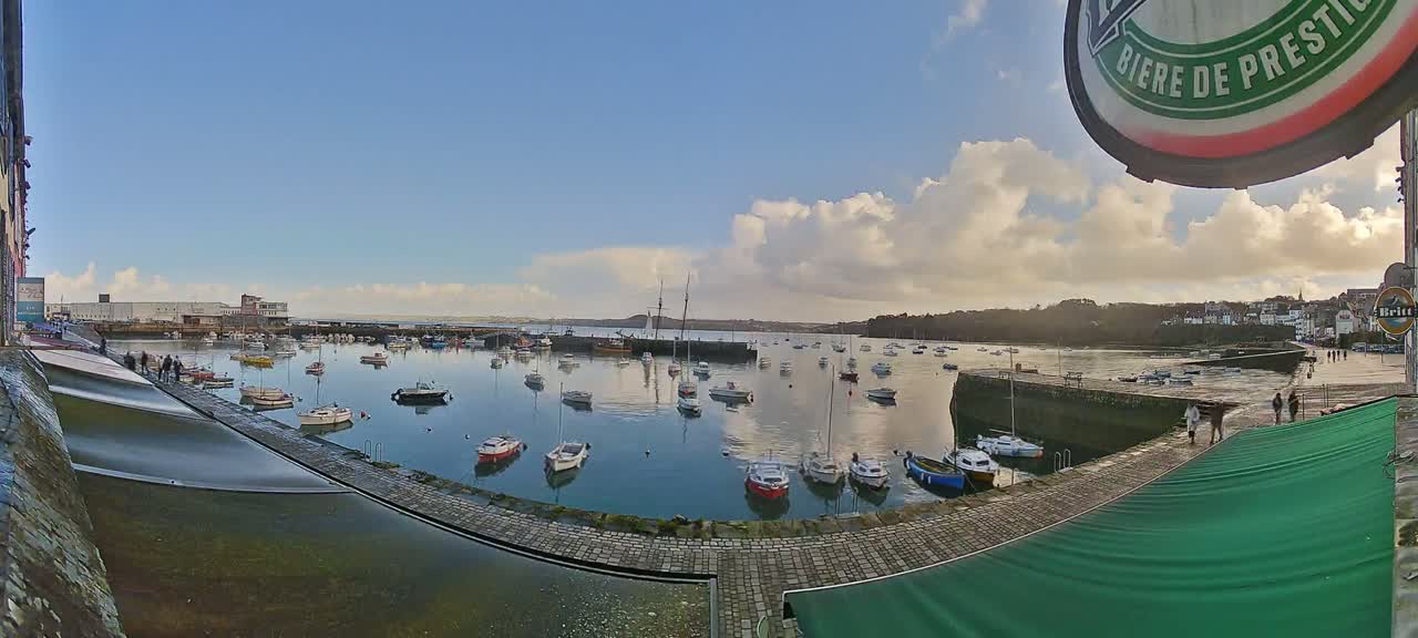 A harbor filled with numerous boats under a partly cloudy sky.