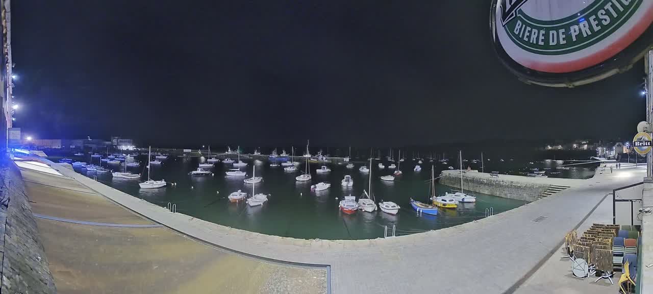 Many boats are moored in a harbor at night.