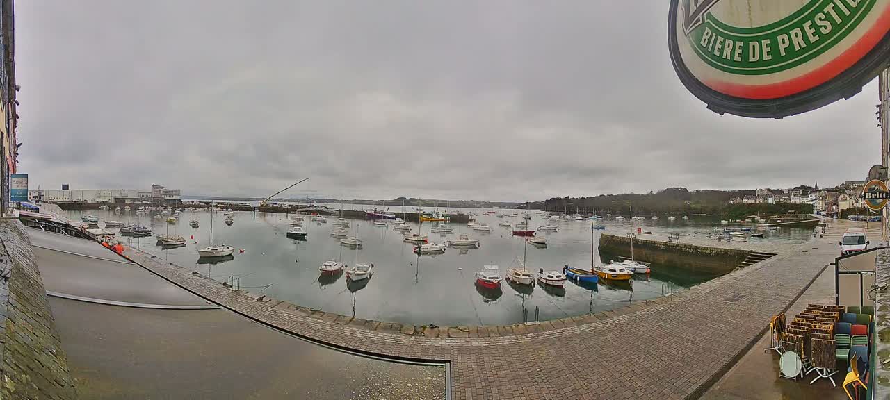 Many small boats are moored in a harbor on an overcast day.