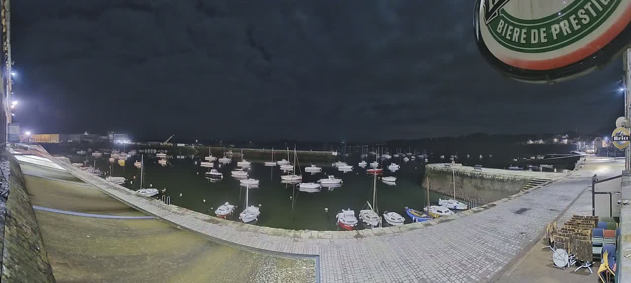 A nighttime view of a harbor filled with numerous small boats under a dark sky.