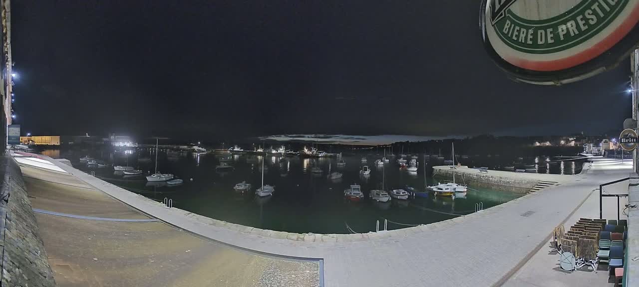 A nighttime view of a harbor filled with numerous boats under a dark sky.