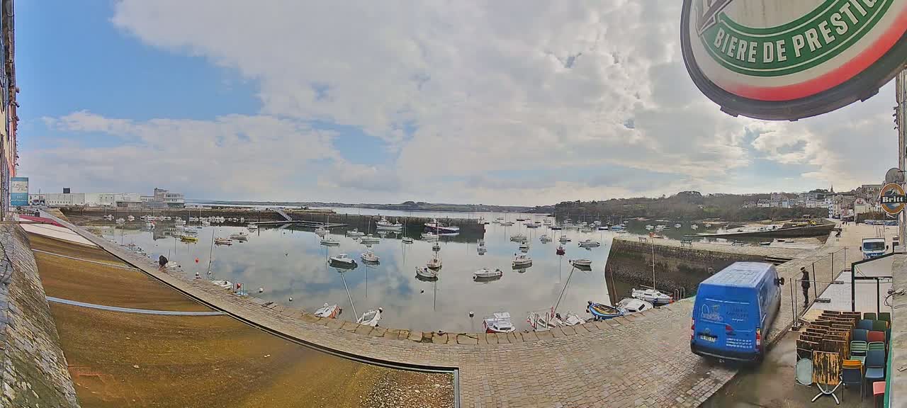 A harbor filled with numerous small boats under a partly cloudy sky.
