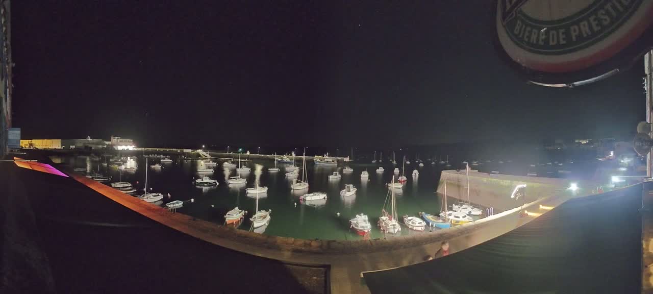 A nighttime view of a harbor filled with numerous small boats under a clear, dark sky.