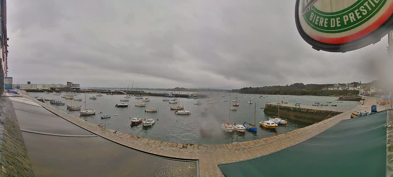 Numerous small boats are moored in a harbor on an overcast day.