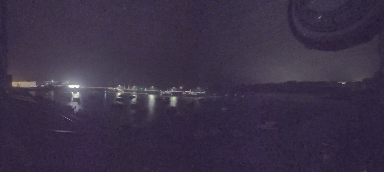 A nighttime view of a harbor with several boats docked under a dark sky.
